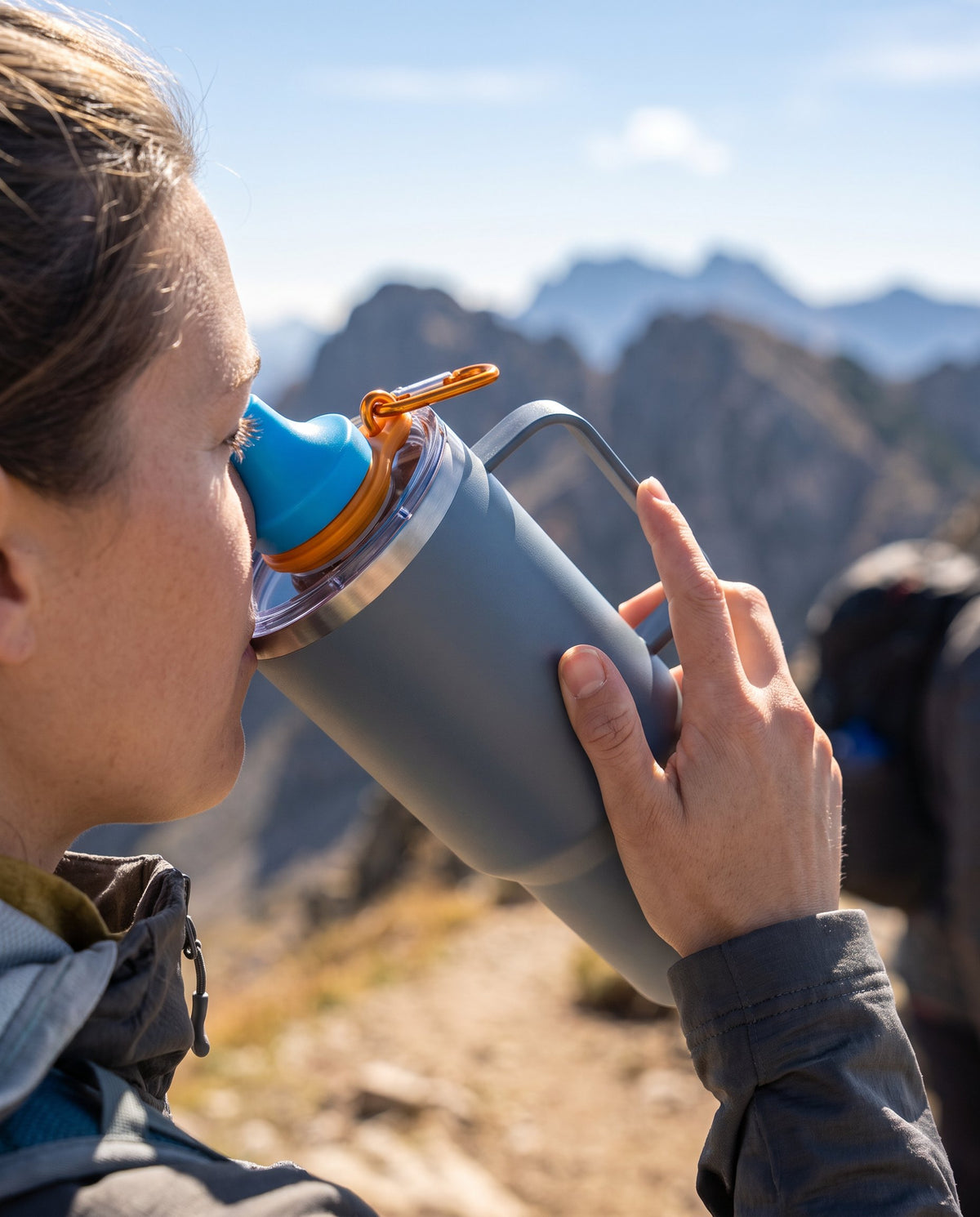 A hiker drinks from a 40 oz tumbler with the Simple Sip lid